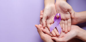 Two pairs of cupped hands, an adult's and a child's, holding a Alzheimer's disease purple awareness ribbon against a purple background